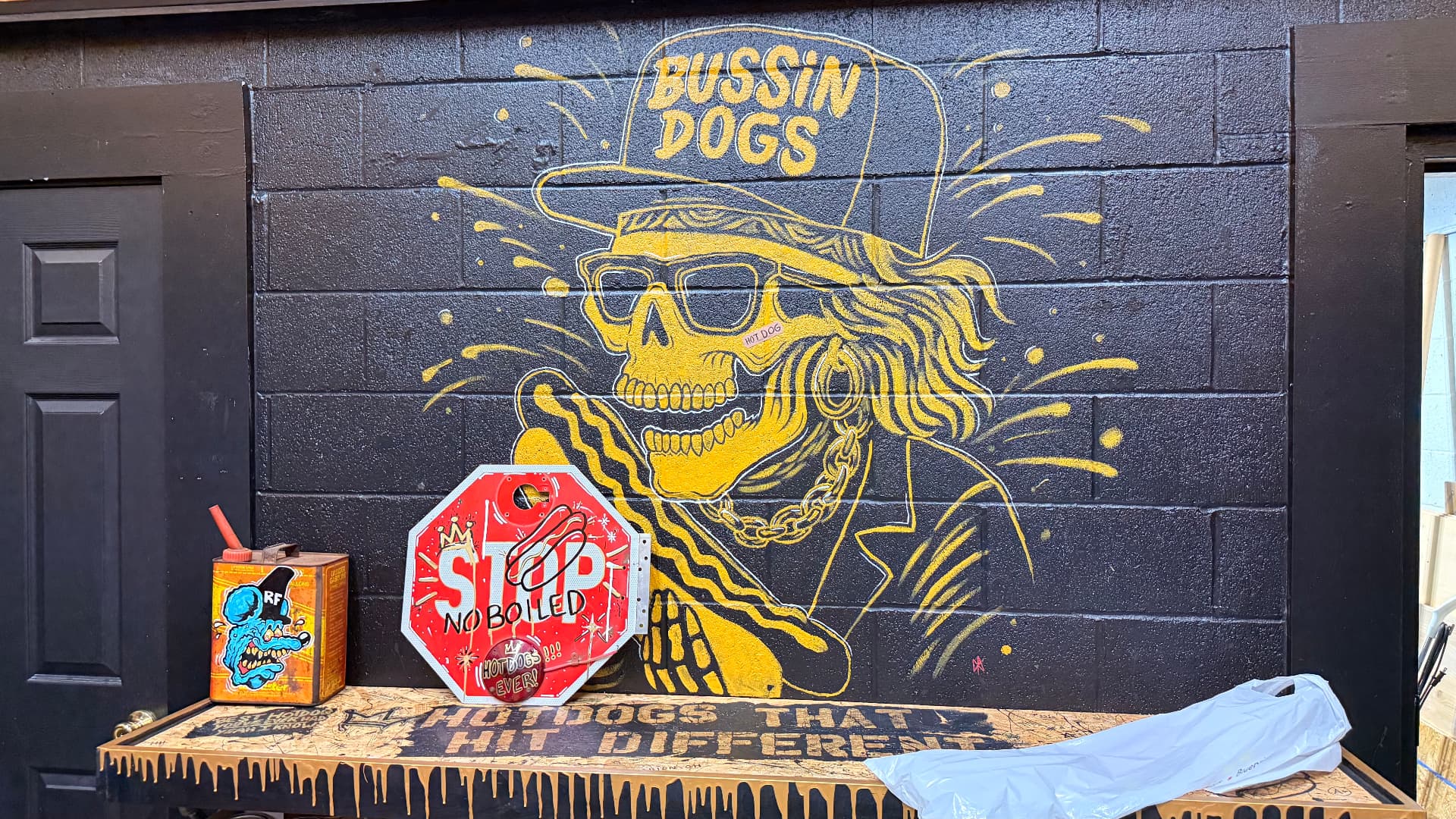 Gold spray-painted Bussin Dogs skull mural on the black block wall inside the Marion, Ohio shop